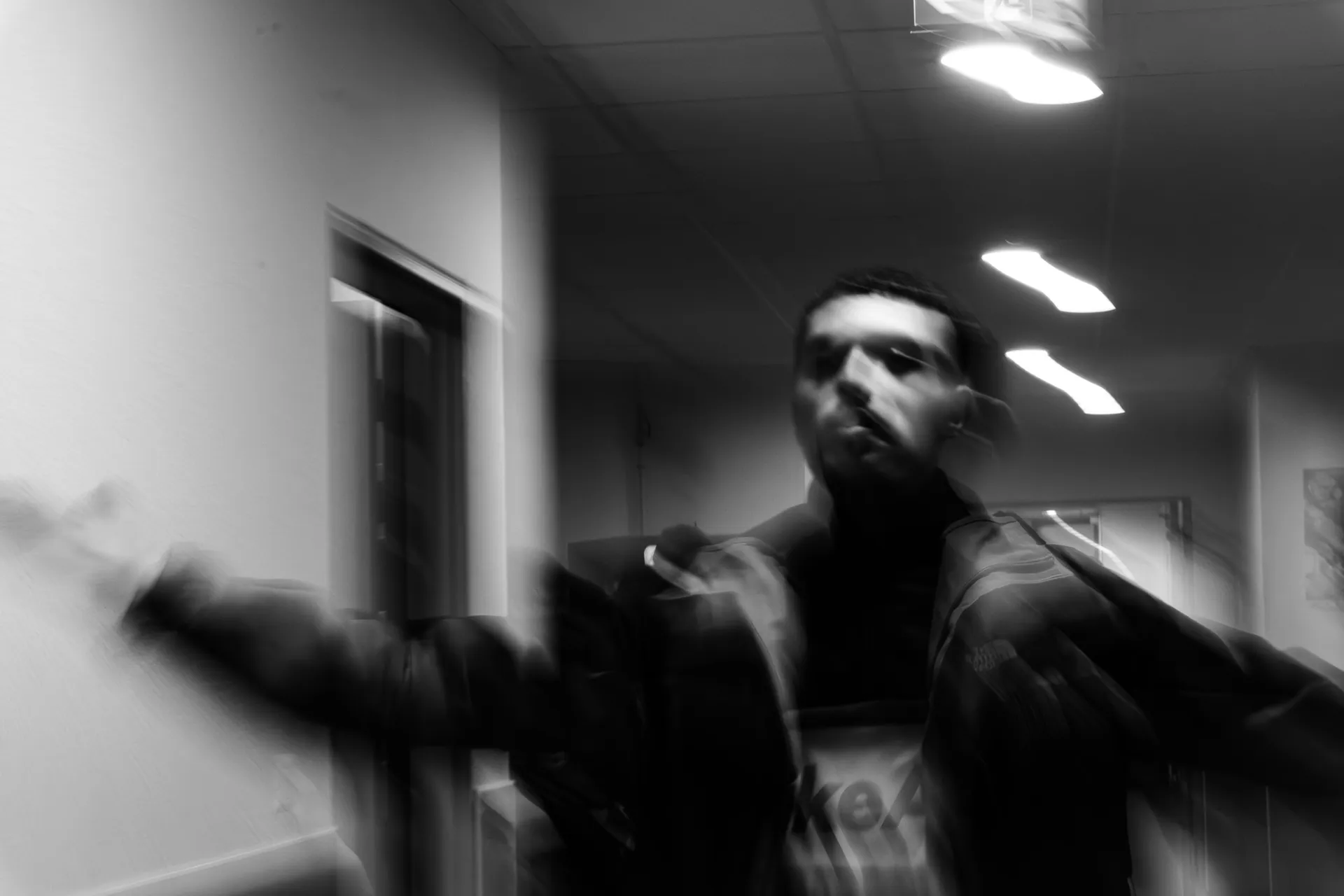 Portrait en noir et blanc d’un homme en mouvement dans un couloir