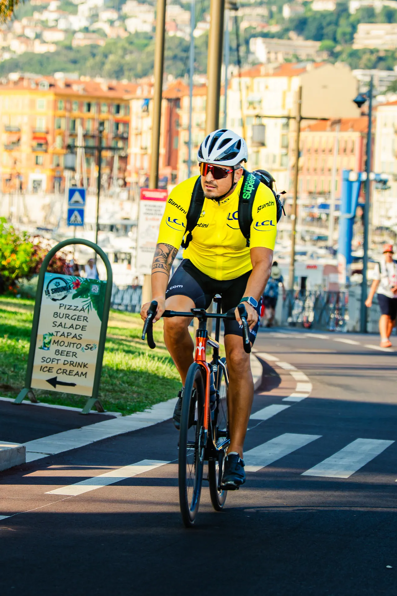 Cycliste en maillot jaune descendant une rue en ville