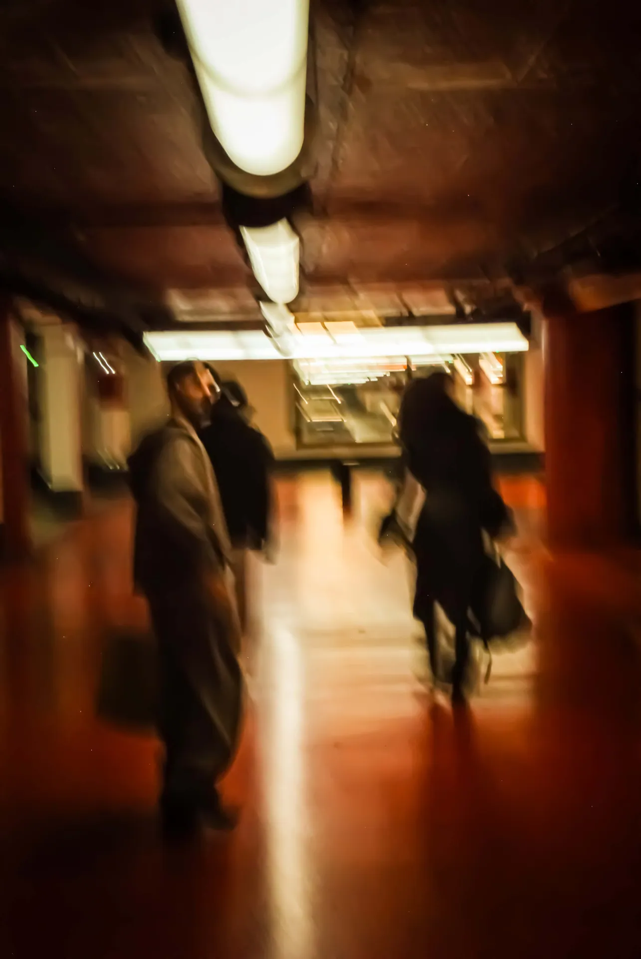 Passants flous dans un couloir souterrain aux tons rouges