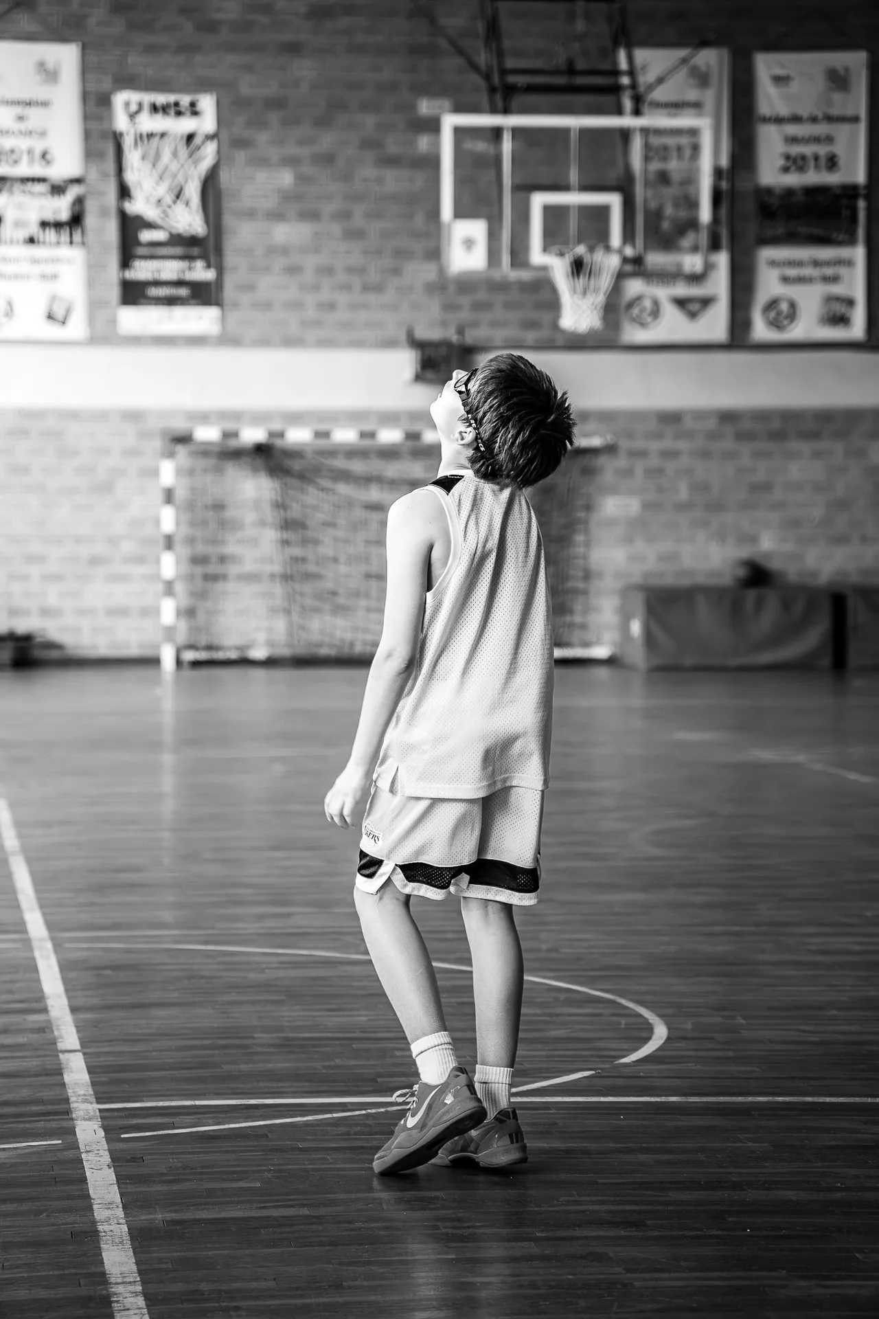 Jeune basketteur seul sur le parquet, en noir et blanc