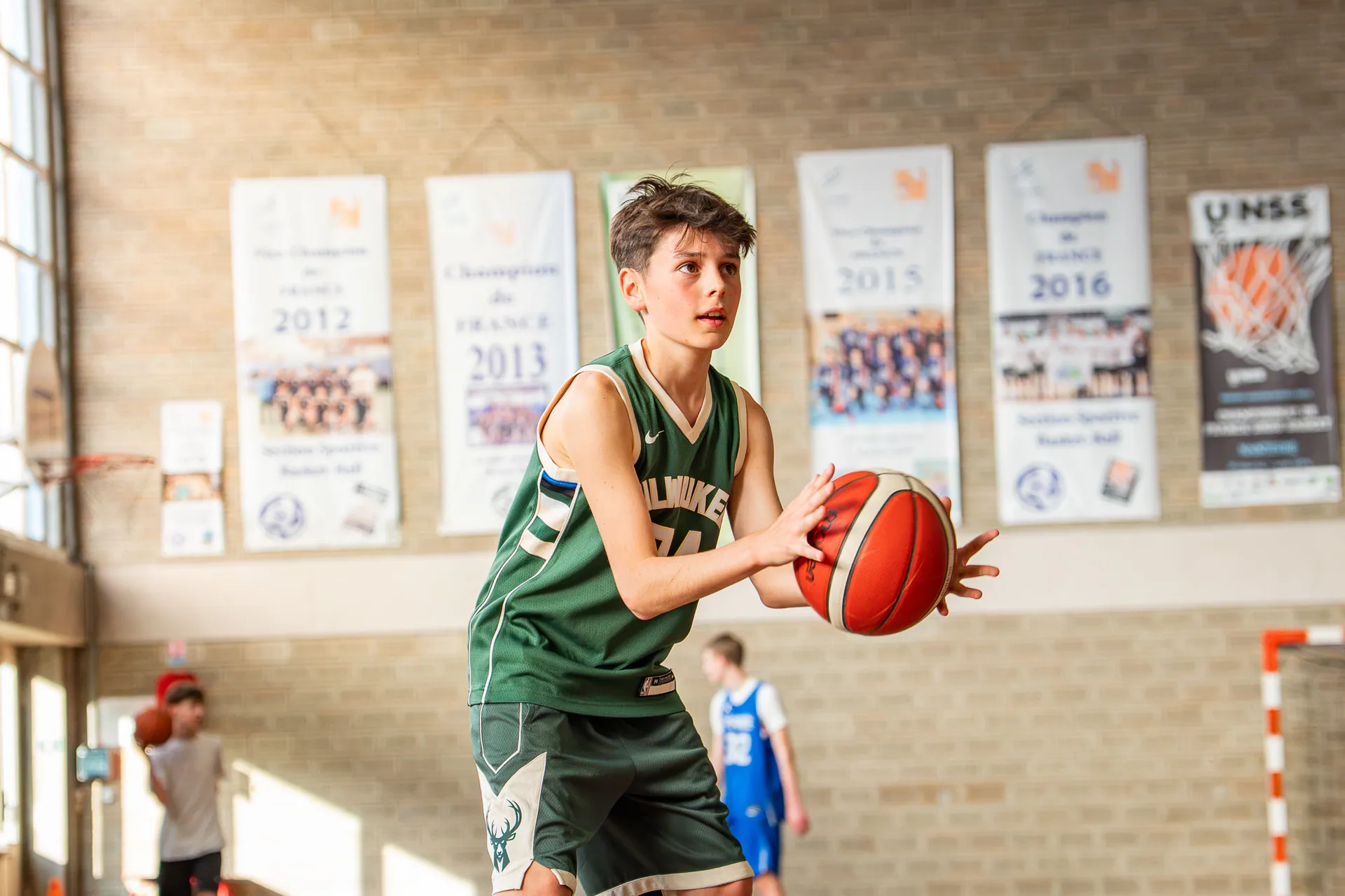 Jeune basketteur en maillot vert préparant un tir dans un gymnase