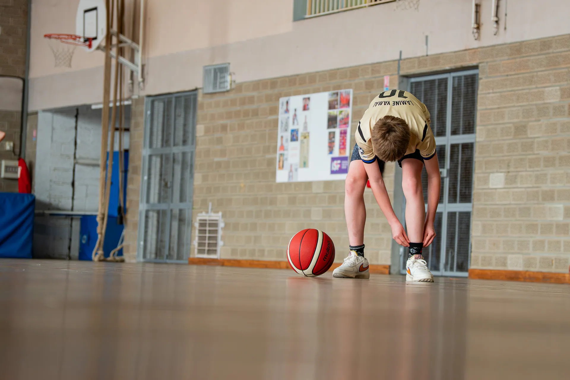 Basketteur reprenant son souffle, mains sur les genoux, ballon au sol