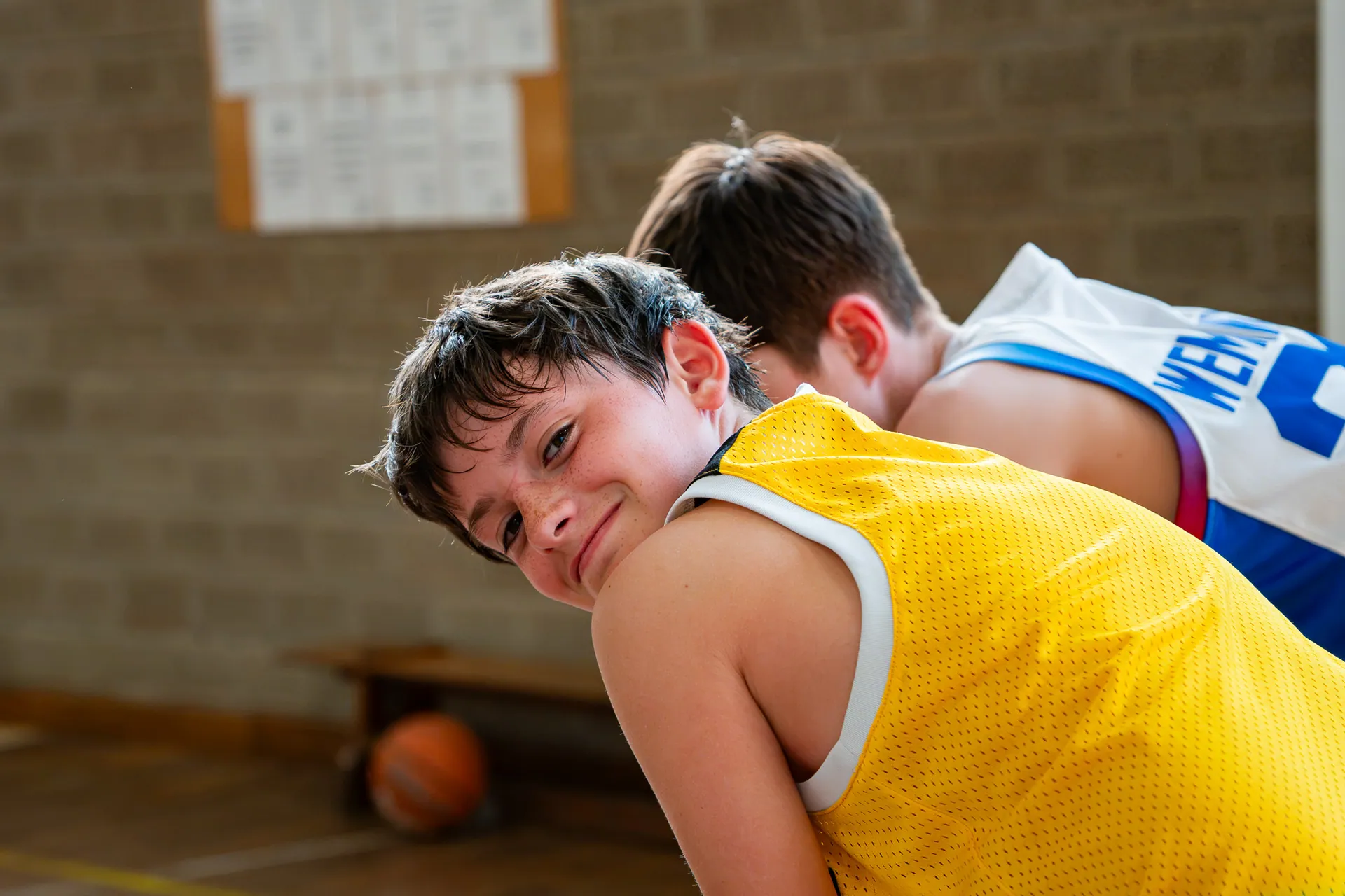 Jeune basketteur souriant par-dessus l’épaule d’un coéquipier