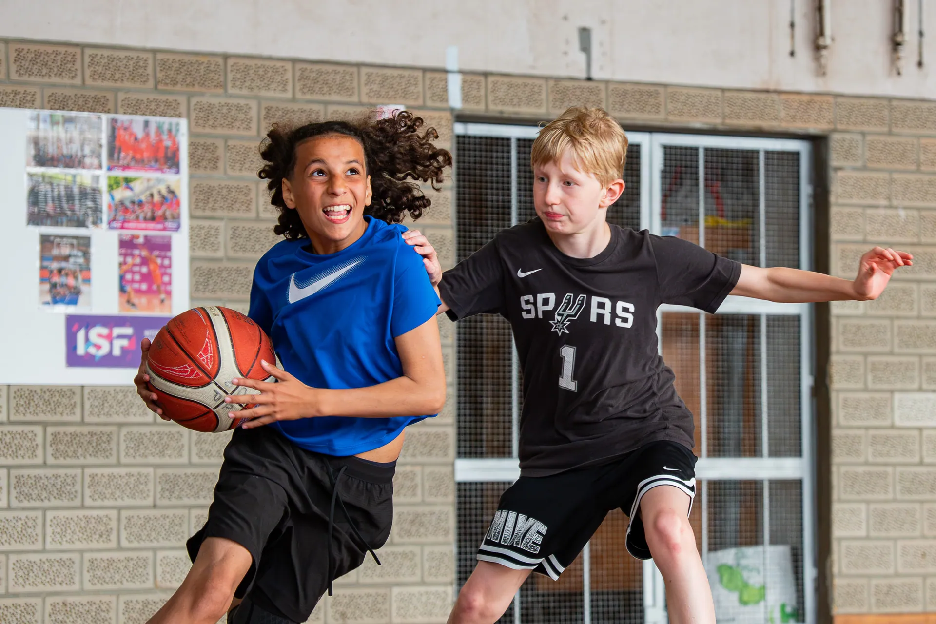Jeune basketteur attaquant le panier face à un défenseur