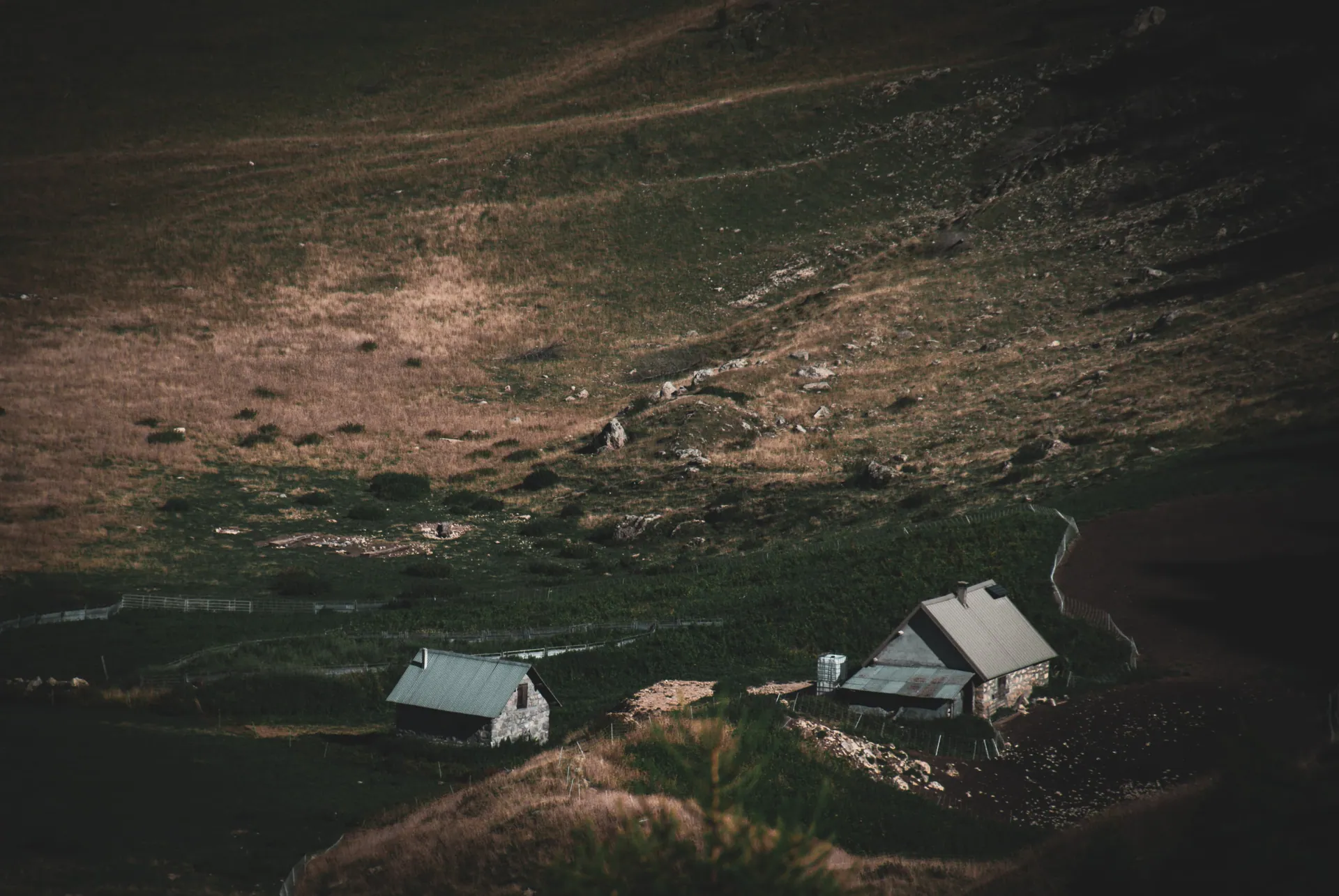 Chalets isolés dans une vallée de montagne aux tons sombres
